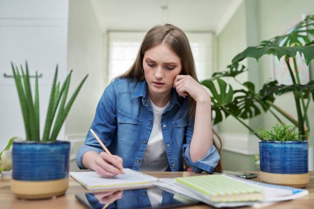 istock Female university student studies at home, writes in a notebook 1356800358
