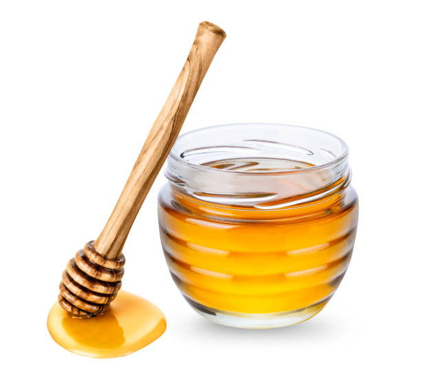 glasgefäß mit honig und hölzernem honiglöffel auf weißem hintergrund - syrup jar sticky isolated objects stock-fotos und bilder