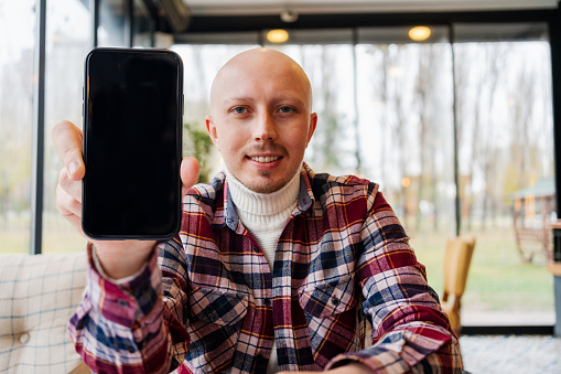 A man holding and showing black mobile phone