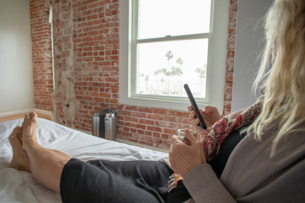 istock Woman reclines on bed and uses smart phone 1356801840