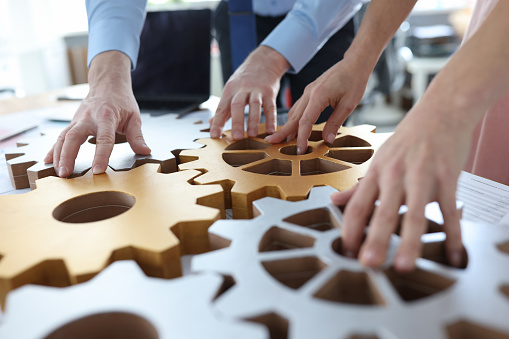 Business people stacking metal gears in office closeup. Brainstorming concept