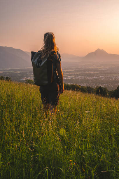 istock Female hiker relaxes on grassy mountain ridge 1356804169