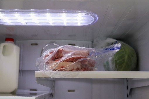 A bag of frozen pork chops thawing in a refrigerator