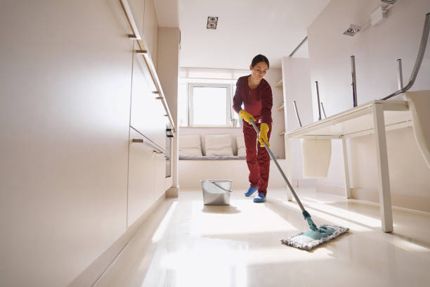 Concentrated uniformed professional janitor doing wet cleaning