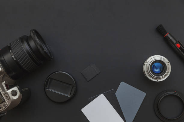 istock Photographer work place with dslr camera system, camera cleaning kit, lens and camera accessory on dark black table background. Hobby travel photography concept. Flat lay top view copy space 1356808457