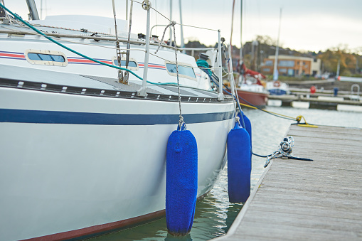 White fenders suspended between a boat and dockside for protection. Maritime fenders