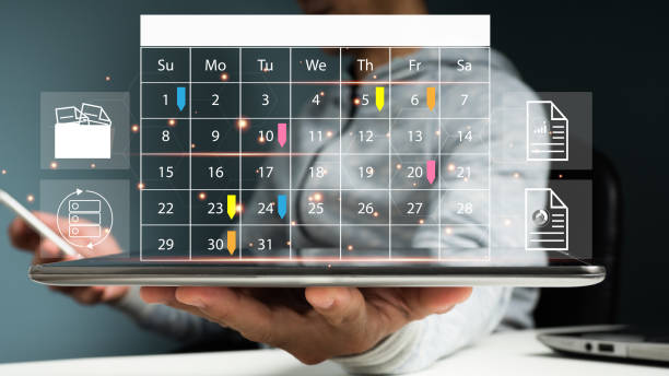 イベントプランナーは、時刻表と議題を使用してイベントの手配とスケジュールを設定します。オフィスのテーブルの上で、ビジネスマンが携帯電話を使ってカレンダーデスクにメモを取っ� - 年表 ストックフォトと画像