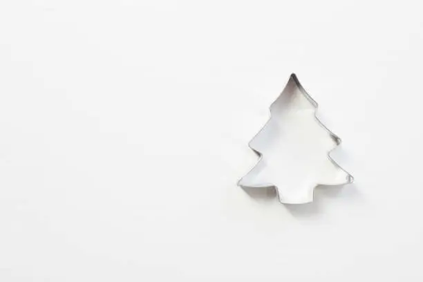 Christmas tree shaped metal cookie cutter on white wooden table