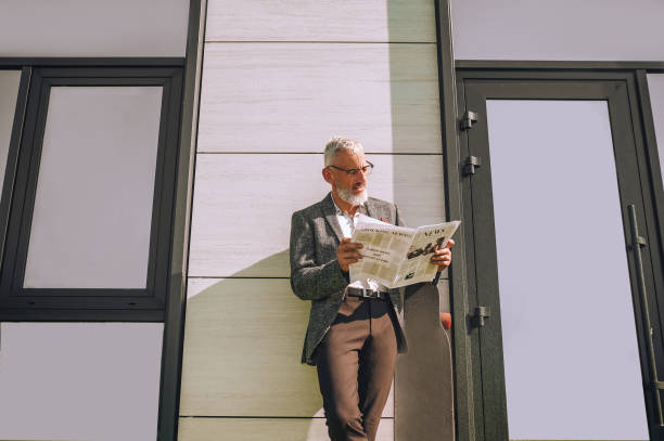A gray-haired businessman with a newspaper in hands