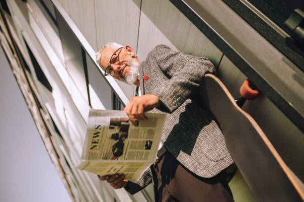 istock A gray-haired businessman reading a newspaper and looking concentrated 1356812086
