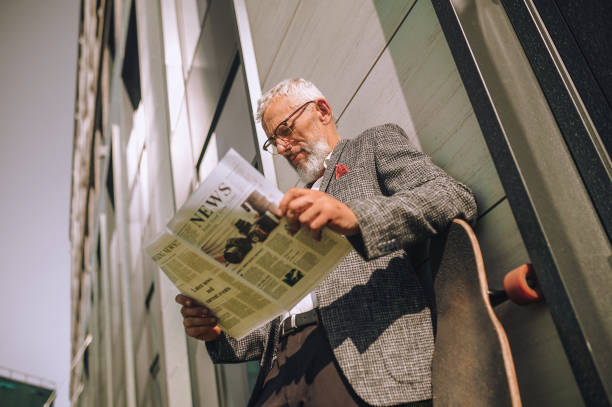 istock A gray-haired businessman reading a newspaper and looking concentrated 1356812089