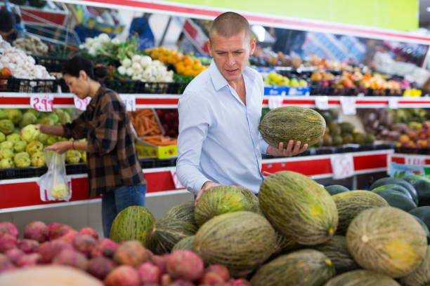 Man choosing melon in fruit and vegetable department of supermarket