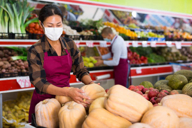istock Greengrocer workers in masks working in salesroom 1356816133