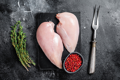 Whole raw Free range chicken in rustic background with rosemary leaf, thyme, lemon. ready to cook.