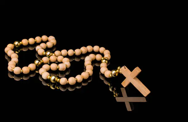 Closeup of wooden Christian cross  prayer rosery  beads on black.Church utensils.