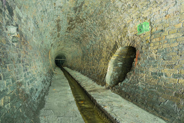 túnel de esgoto de tijolos velhos. rio subterrâneo ou velho coletor de água da chuva do século 19. - 19th hole - fotografias e filmes do acervo