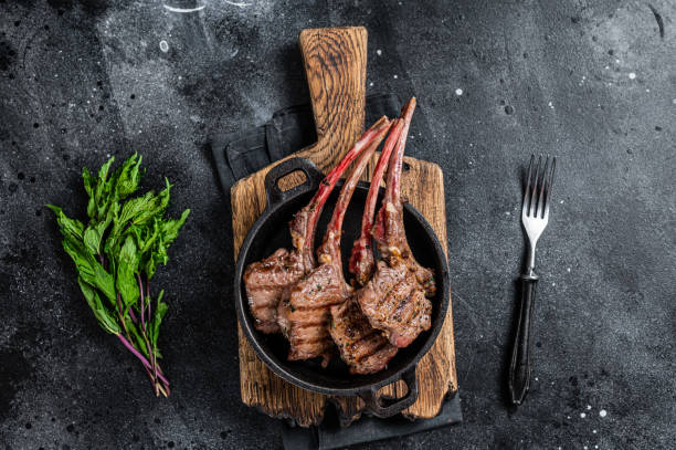 istock BBq Grilled lamb mutton chops steaks in a pan. Black background. Top view 1356822525