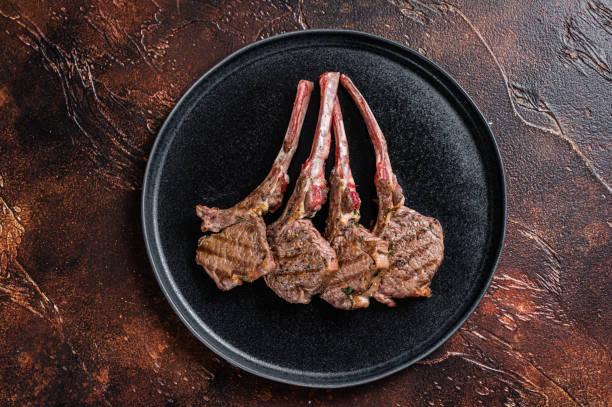 istock BBQ Grilled lamb chops steaks in a plate. Dark background. Top view 1356822635