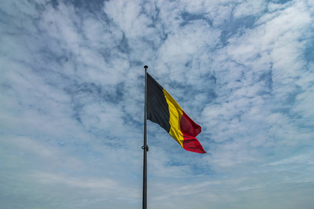 Belgian national flag with a cloudy sky
