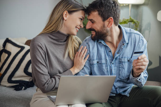 istock Young couple using laptop and doing activities E-commerce at home 1356823455