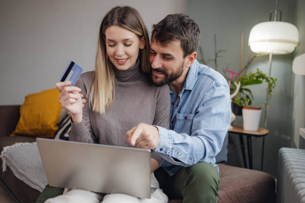 istock Young couple using laptop and doing activities E-commerce at home 1356823712