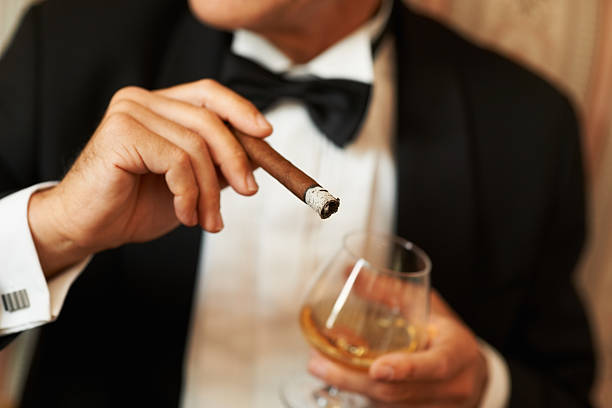 Gentlemen's choice Closeup of a wealthy man in a tuxedo holding a cigar and glass of brandy chivalry stock pictures, royalty-free photos & images