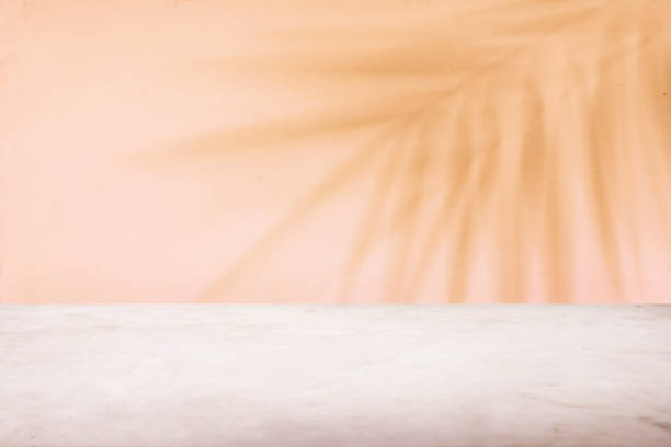 istock Tropical palm tree shadow on peach wall and luxury marble table for product placement. 1356825413