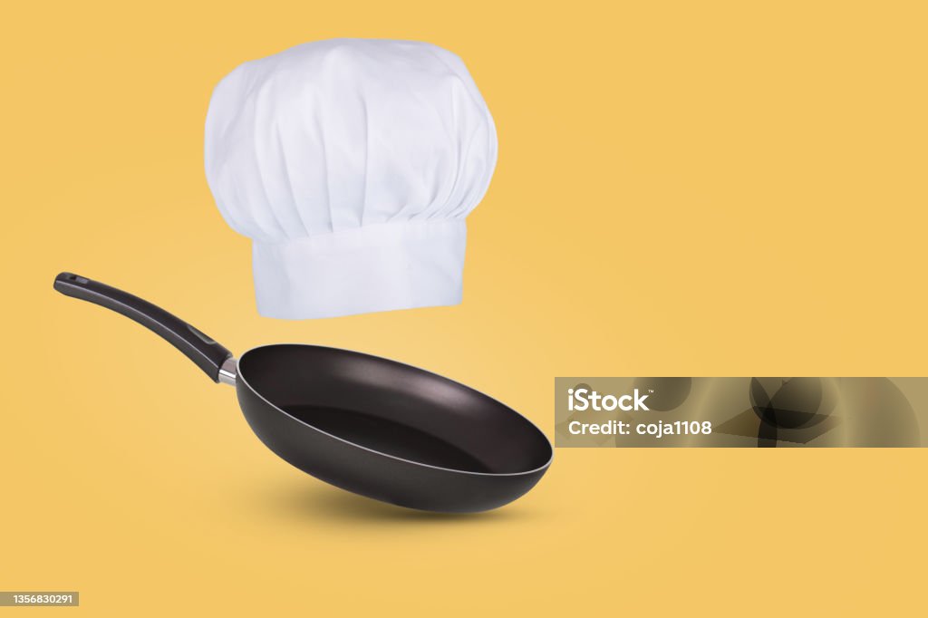 Chef hat floating in air isolated on a blue background. Creative business concept. Frying pan and Chef hat floating in air isolated on a pastel yellow background. Creative business concept. Chef symbol. Abstract Stock Photo