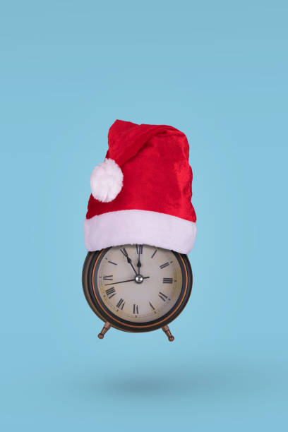 istock Alarm clock in a Santa Claus hat flying in air  on a blue background. 1356830861