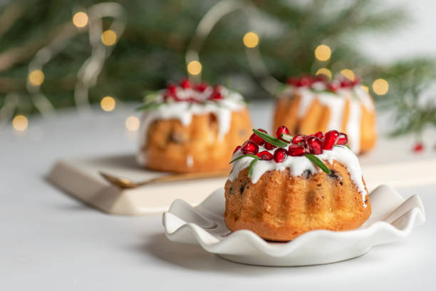 Christmas cake . Christmas mini bundt cake with sugar glaze and fruit Christmas cake .Christmas mini bundt cake with sugar glaze and pomegranate fruit served in a plate, with Christmas decoration on a white background isolated .Stock photo. christmas cake stock pictures, royalty-free photos & images