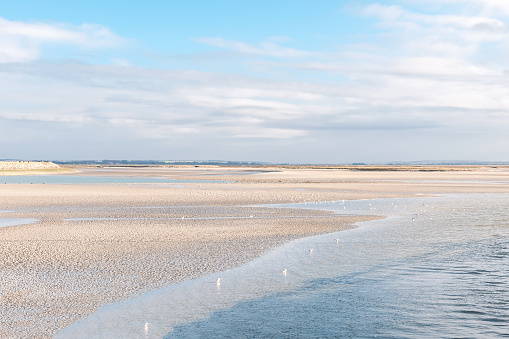 It's low tide on the beach of Schiermonnikoog. The clouds are reflected on the wet wadden sea.