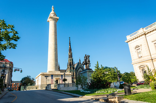 Baltimore, Maryland, United States of America - September 6, 2016. Washington Place in Baltimore, MD, with the Washington Monument, Marquis de Lafayette Statue and Mt. Vernon Place United Methodist Church. The colossal Doric column of white marble was completed in 1829. View on a sunny day, with cars and people.