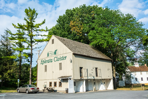 Ephrata, Pennsylvania, United States of America - September 9, 2016. The Barn building of Ephrata Cloister, currently occupying the Museum Store, in Ephrata, PA. The building was once a part of the Shady Nook Farm and housed animals and equipment. Exterior view with a car.