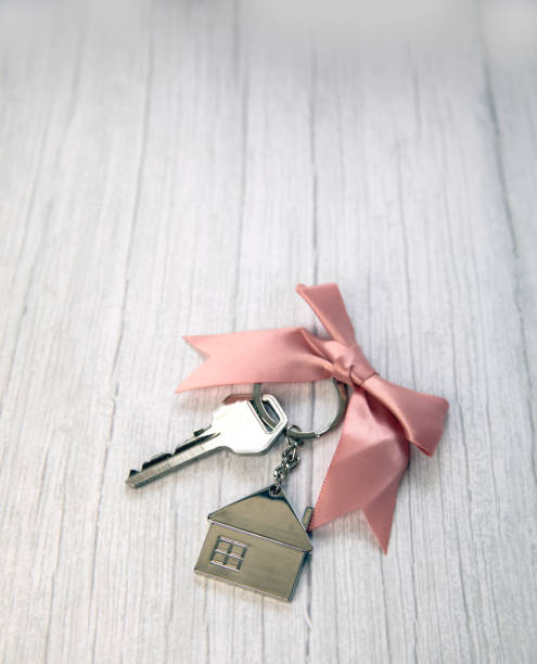 New keys of a house silver with keychain of little house top view with copy space and white wooden background, stock photo