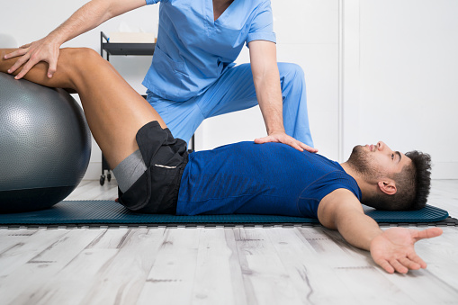 El fisioterapeuta ayuda a un paciente joven y guapo con ejercicios de pilates. Foto de alta calidad photo
