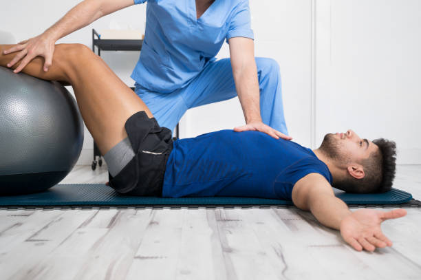 el fisioterapeuta ayuda a un paciente joven y guapo con ejercicios de pilates. foto de alta calidad - biomecánica fotografías e imágenes de stock