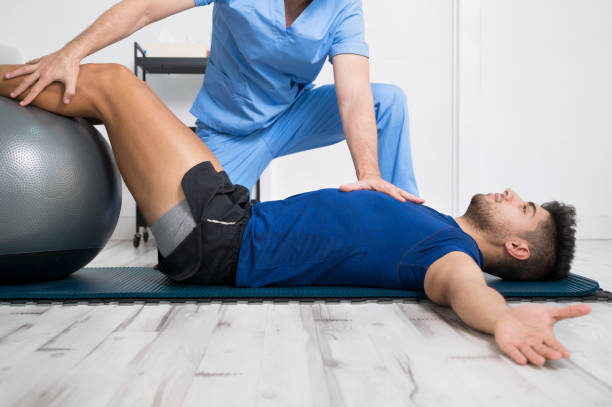 il fisioterapista aiuta un bel giovane paziente con esercizi di pilates. foto di alta qualità - therapy foto e immagini stock