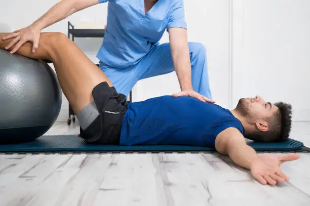 Physiotherapist helps handsome young patient with pilates exercises. High quality photo