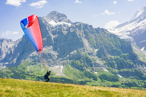 Grindelwald, Switzerland - August 15. 2021: First mountain, in the Swiss Alps in the Canton of Bern. Hang glider start to fly between Swiss peaks.