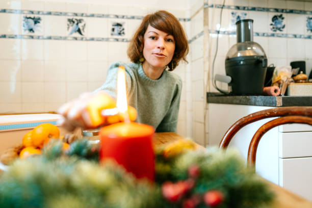 istock Woman lighting candle on Advent wreath on dinner table 1356840613