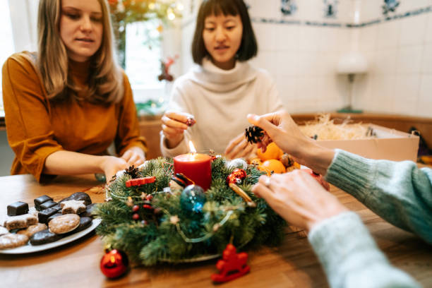 istock Women decorating advent wreath with decorative ornaments on christmas table 1356840687