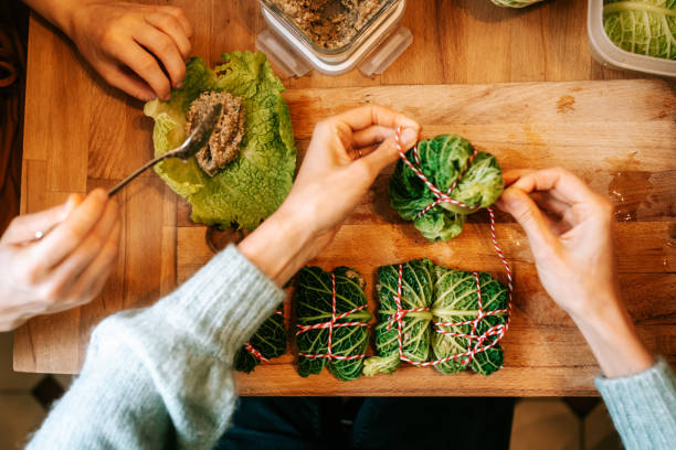 istock Hands of women making stuffed Christmas Cabbage rolls on kitchen table 1356840817