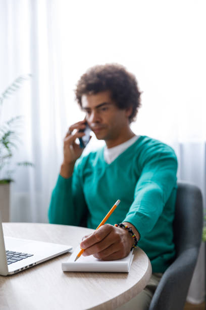 istock Male entrepreneur on a conference call writing notes 1356841744