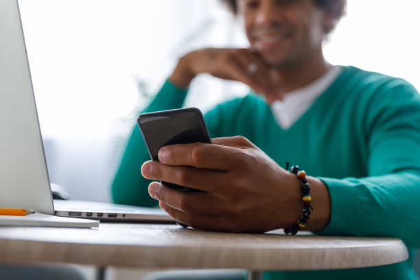 istock Male entrepreneur checking text messages on smart phone while working from home 1356841748