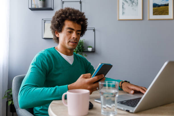 istock Man responding to a text via smart phone while working from home 1356841751