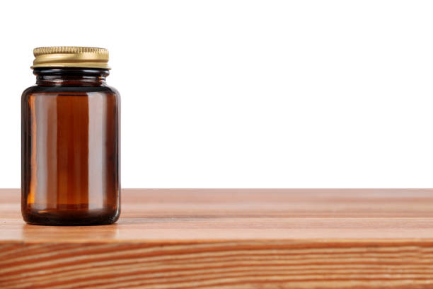 Wooden table on white background with brown medical bottle. Concept of herbal medicine, pill dish, tablet container.