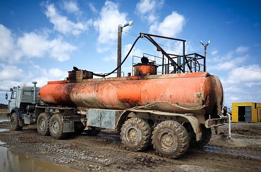 Gasoline tanker, oil storage tank, oil drilling rig, technological area, Sakhalin island. Blue sky, dirty earth road with tracks