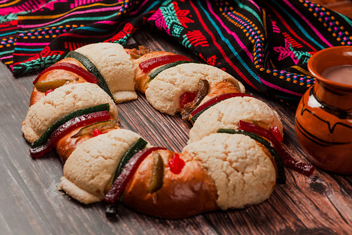 Rosca de reyes or Epiphany cake and clay mug of mexican hot chocolate on a wooden table in Mexico Latin America