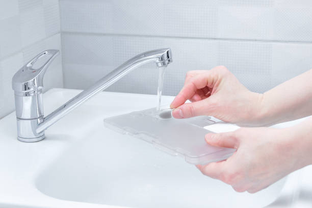 istock Pours water from the tap into the container for robot vacuum cleaner. 1356848628