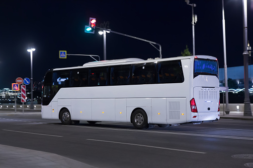 Tourist bus moves at night along the illuminated city street